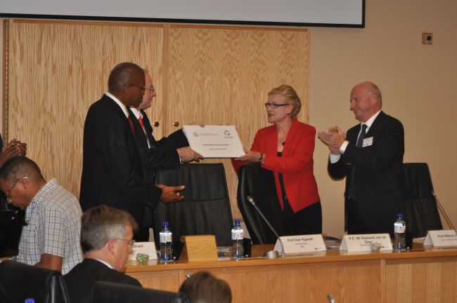 Prof Dan Kgwadi gives a plaque to the new WTO Chair, Prof Wilma Viviers